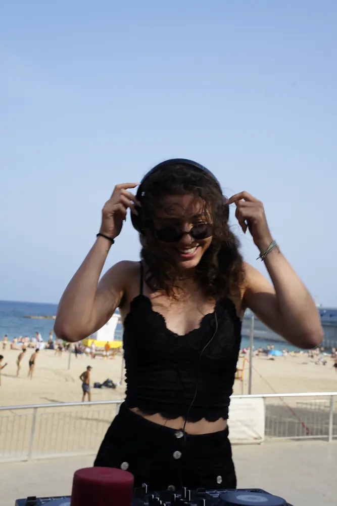 A woman adjusting her sunglasses on the beach
